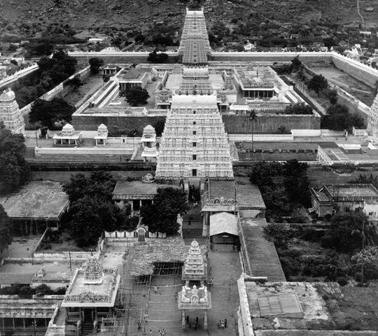 Black-and-white aerial view of the Arunachaleswara temple complex with its tall gopurams, walled courtyards and shrines, the hill slope behind. Whole picture.