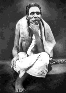 Portrait of Sri Seshadri Swami seated cross-legged, a cloth over his shoulders, hand raised to his chin.