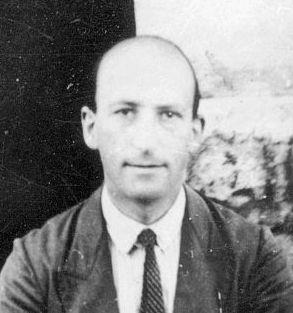 Black-and-white head-and-shoulders portrait of a balding man in a jacket and striped tie. Whole picture.