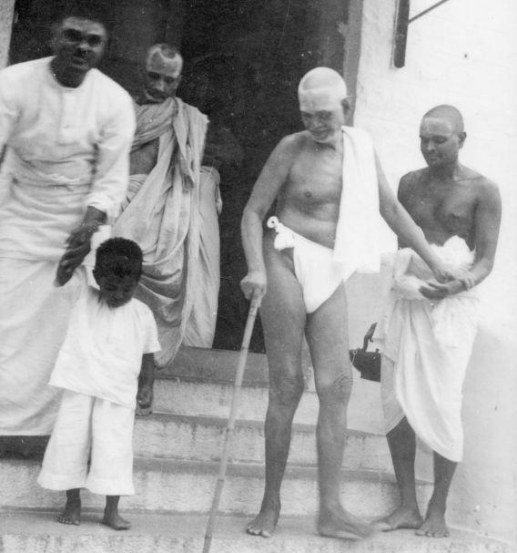 Bhagavan is holding Vaikuntavasar’s hand. The child is ‘Ramana’, son of Dr. T. N. Krishnaswami. Eknath Rao and Amrithanatha Yati are also seen.