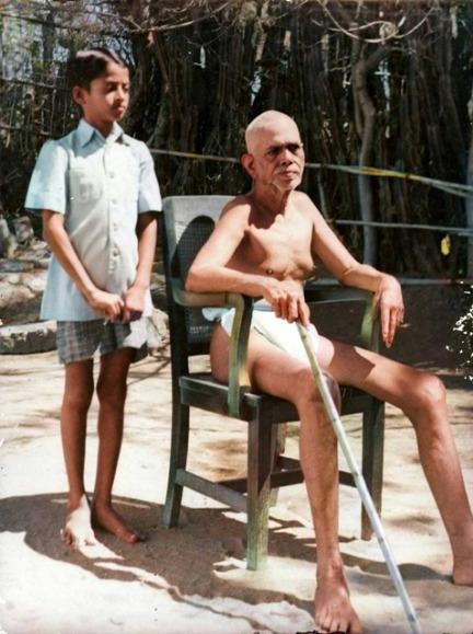 colour photo of the author as a boy standing behind Sri Bhagavan seated on a chair, 1946