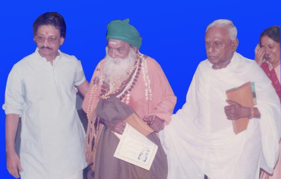 Yogi Ramsuratkumar with two men against blue background