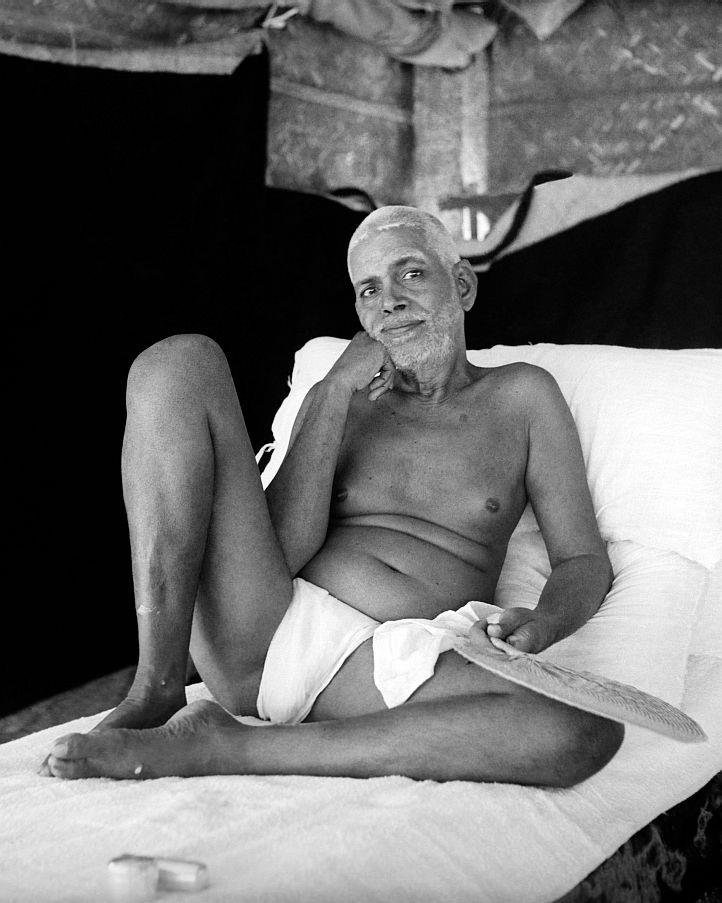 black-and-white photo of Sri Bhagavan reclining on couch, right hand on chin