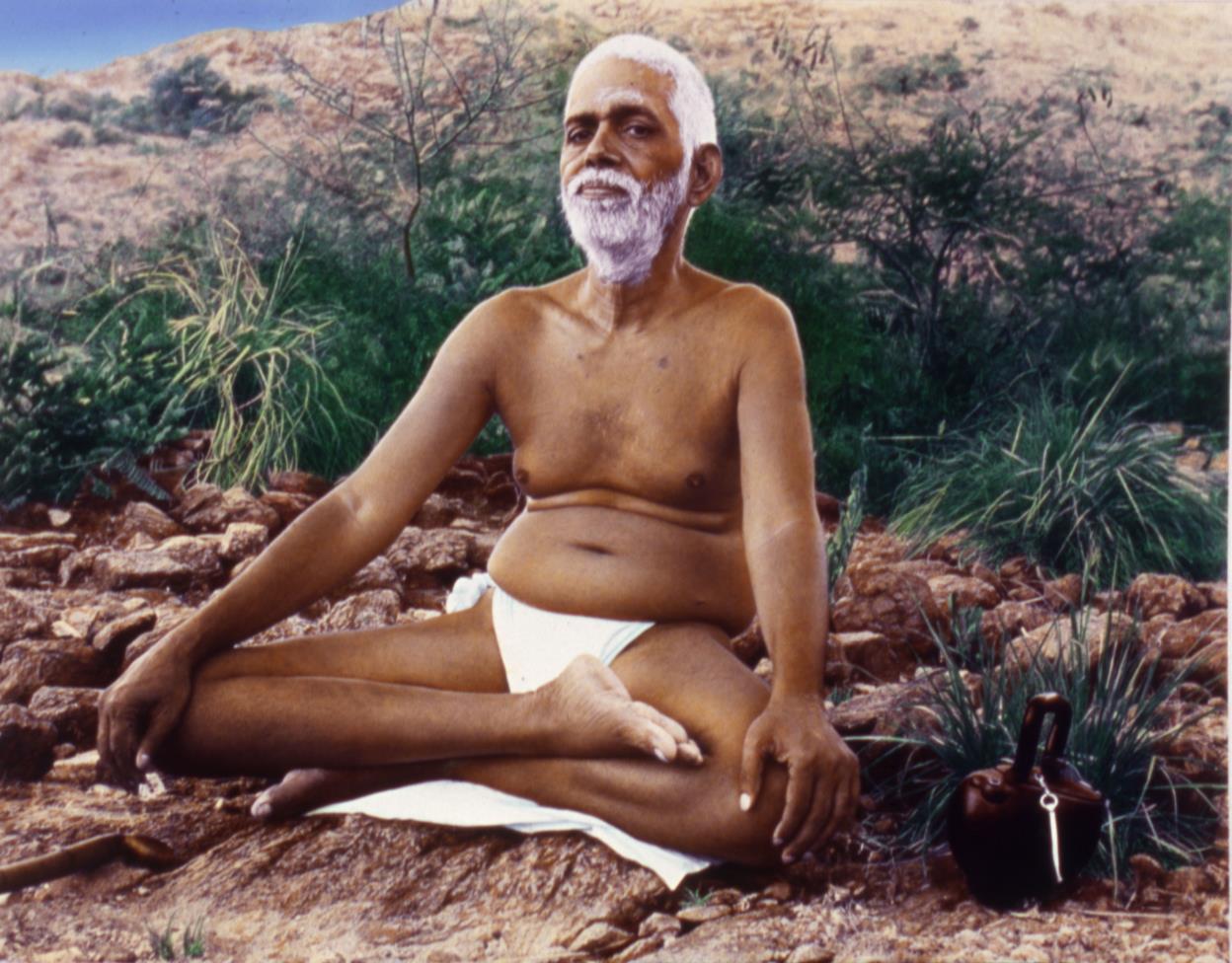 photo of Sri Bhagavan seated on rocky ground with a kamandalu beside him