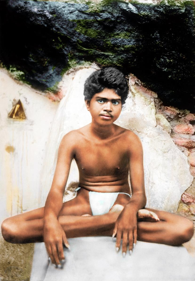 colour photo of the young Sri Ramana seated inside Virupaksha Cave