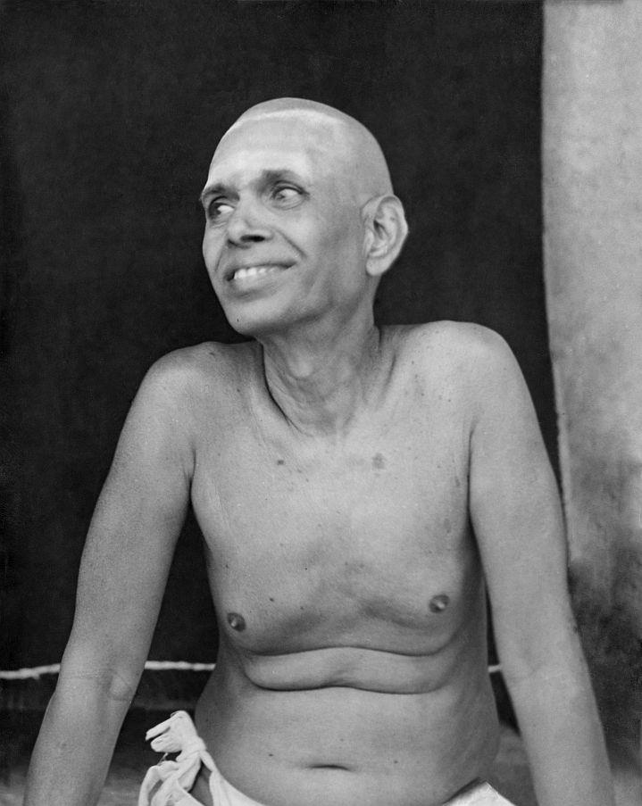full-page black-and-white photo of Sri Bhagavan, head shaven, smiling and glancing to his right