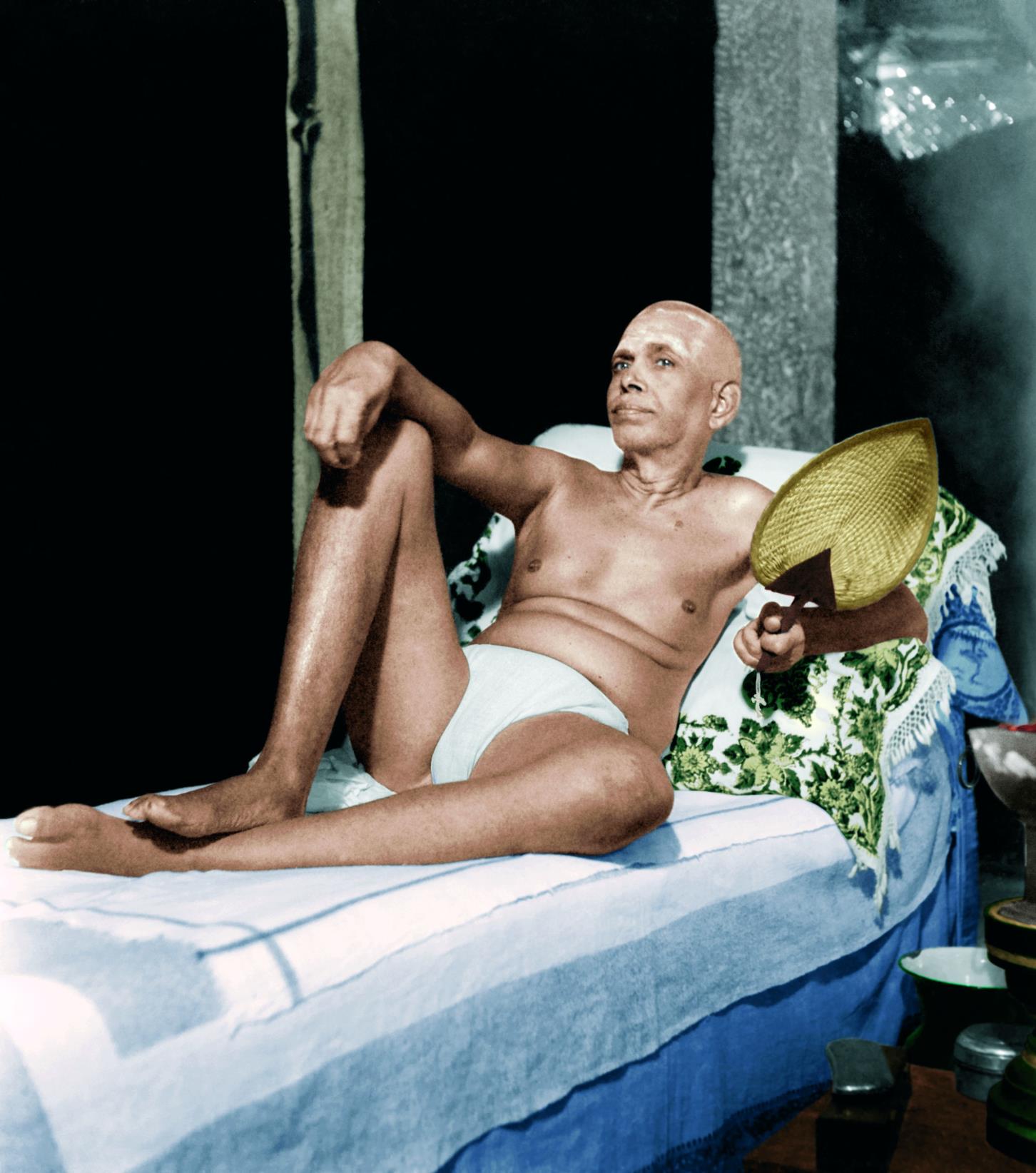full-page colour photo of Sri Bhagavan reclining on his couch holding a palm-leaf fan