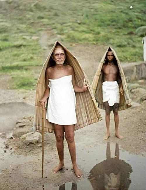 photo of Sri Bhagavan and an attendant, each under a country umbrella