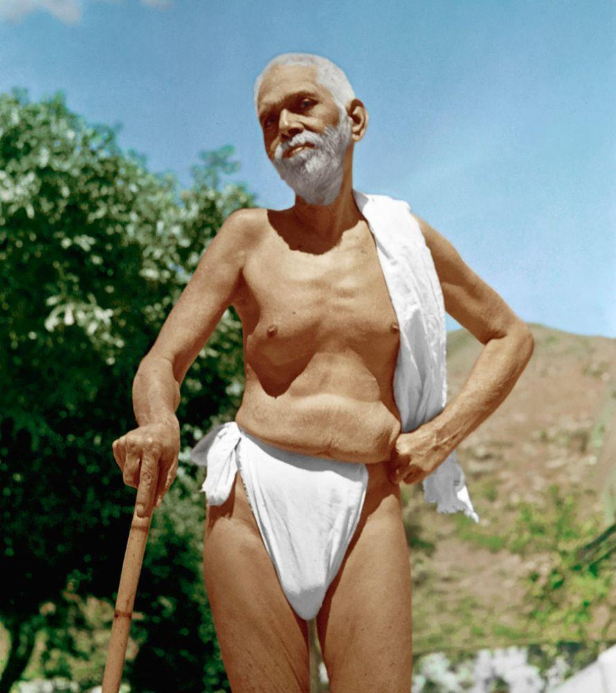 full-page colour photo of Sri Bhagavan standing outdoors with a stick, white cloth over shoulder