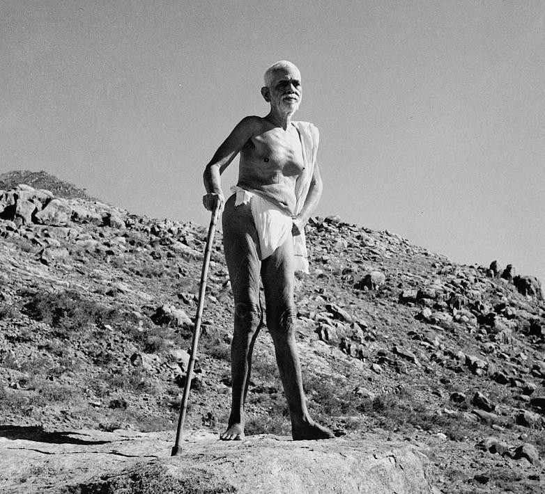 black-and-white photo of Sri Bhagavan standing with a staff on a rocky hillside