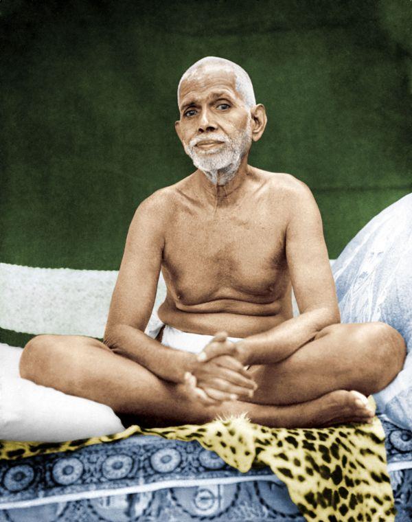 colour photo of Sri Bhagavan seated cross-legged on a couch with leopard skin, hands clasped