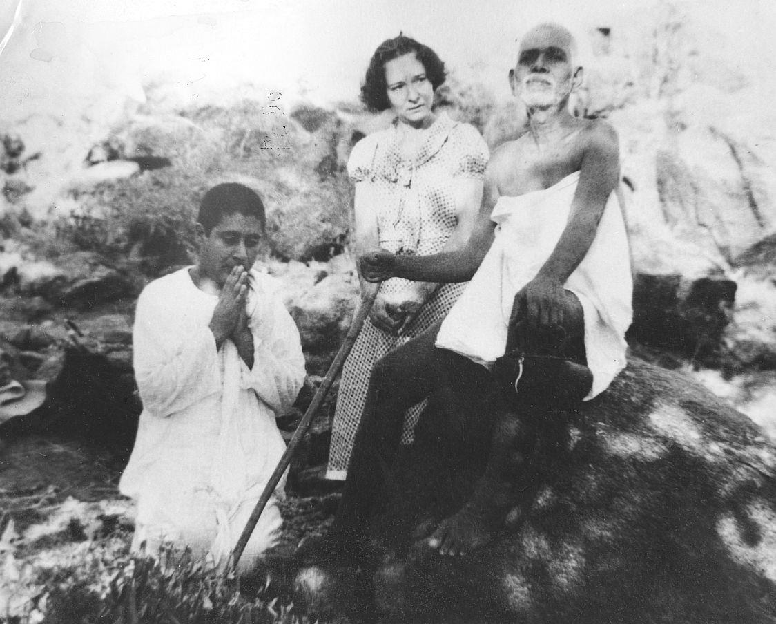 photo of Sri Lakshman Joo kneeling in obeisance before Sri Bhagavan seated on a rock on the Hill, with Eleanor Pauline Noye standing between