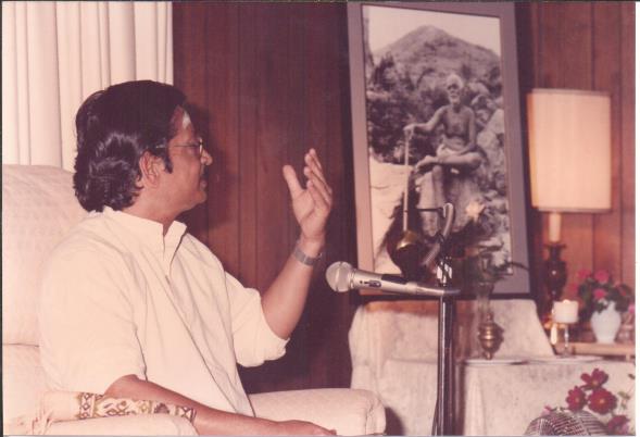 photo of Ganesan speaking seated in an armchair with microphone
