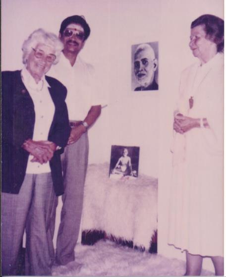 photo of Ganesan with two elderly women devotees before a picture of Sri Bhagavan