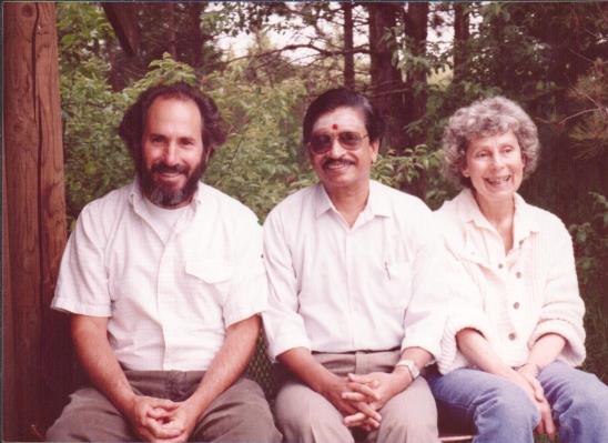 photo of Ganesan seated on a bench with two people