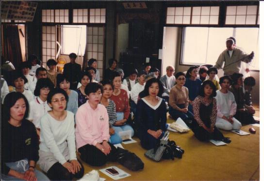 photo of an audience seated on the floor of a hall, Kyoto