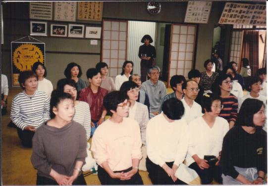 photo of an audience seated on the floor of a hall, Kyoto