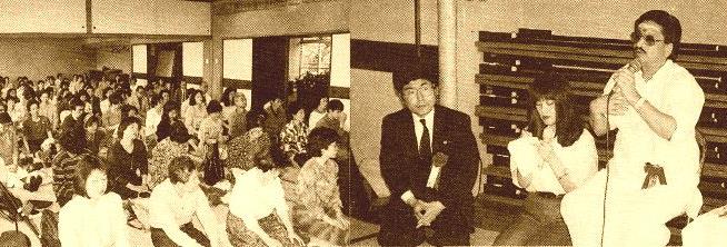 panoramic photograph of a hall full of seated people with Ganesan speaking into a microphone, Tokyo