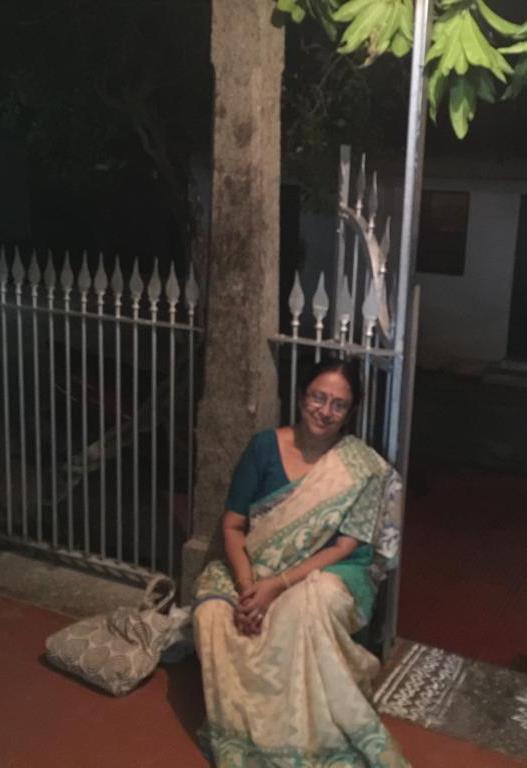 woman in saree seated outdoors near a gate at night