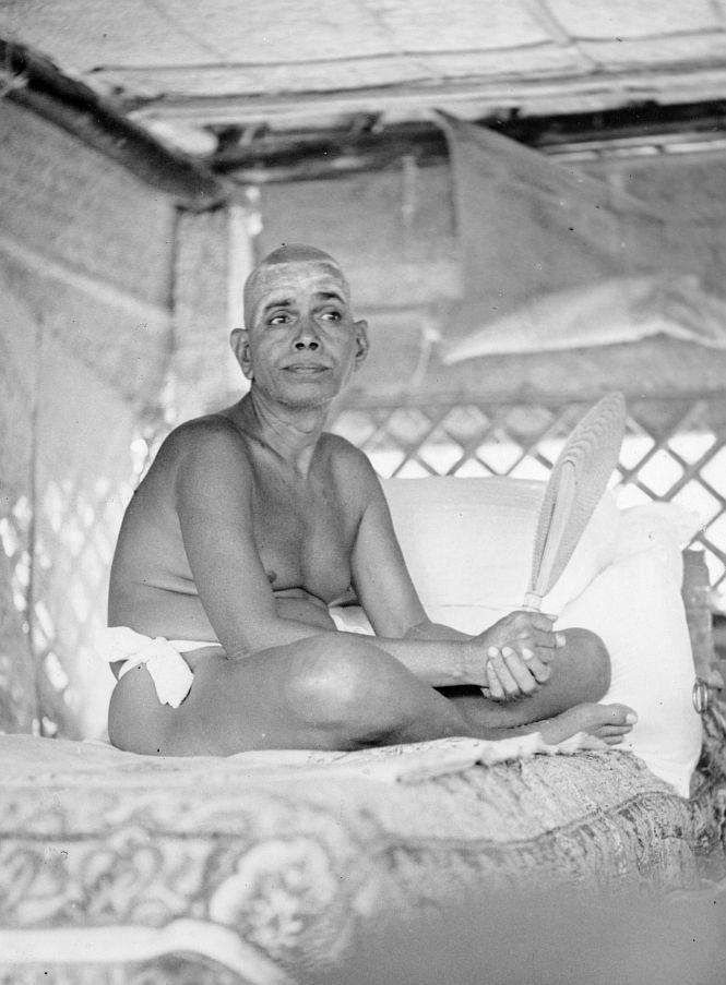 photo of Sri Bhagavan seated on couch holding a palm-leaf fan