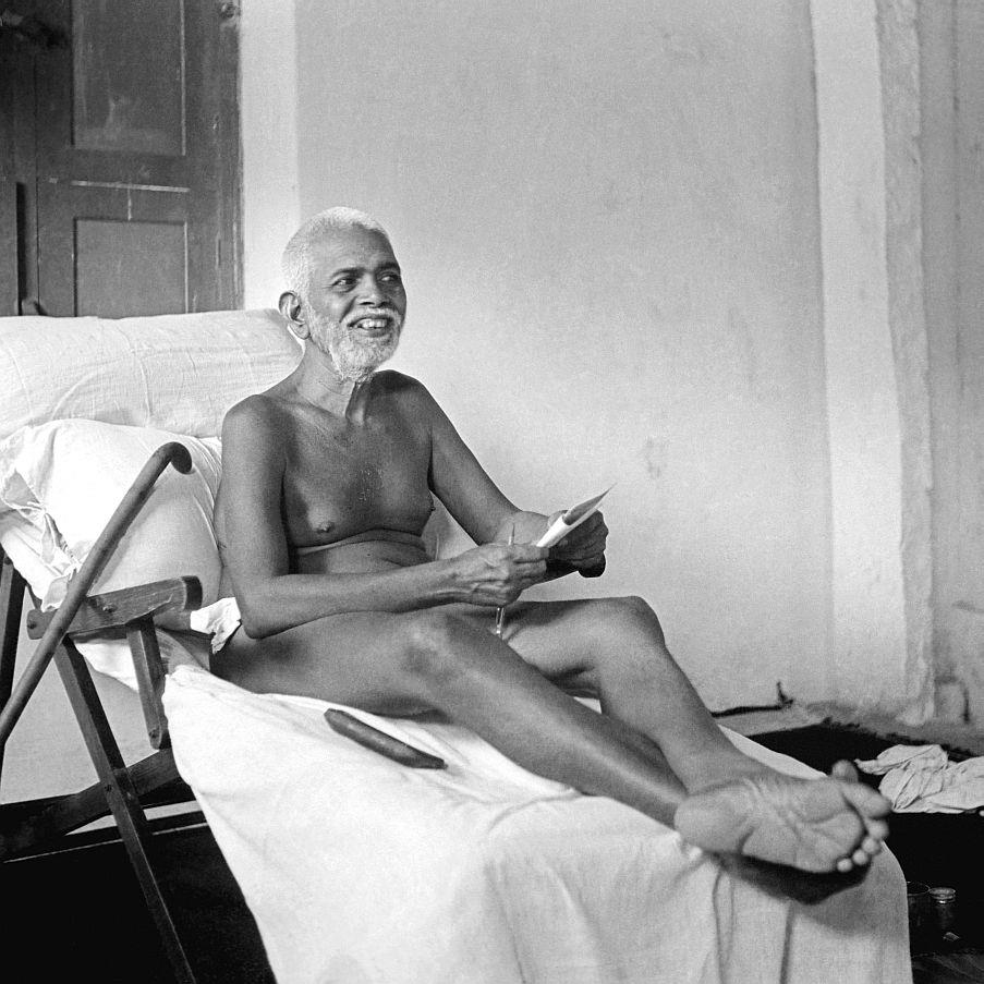 photo of Sri Bhagavan reclining, smiling, holding a paper